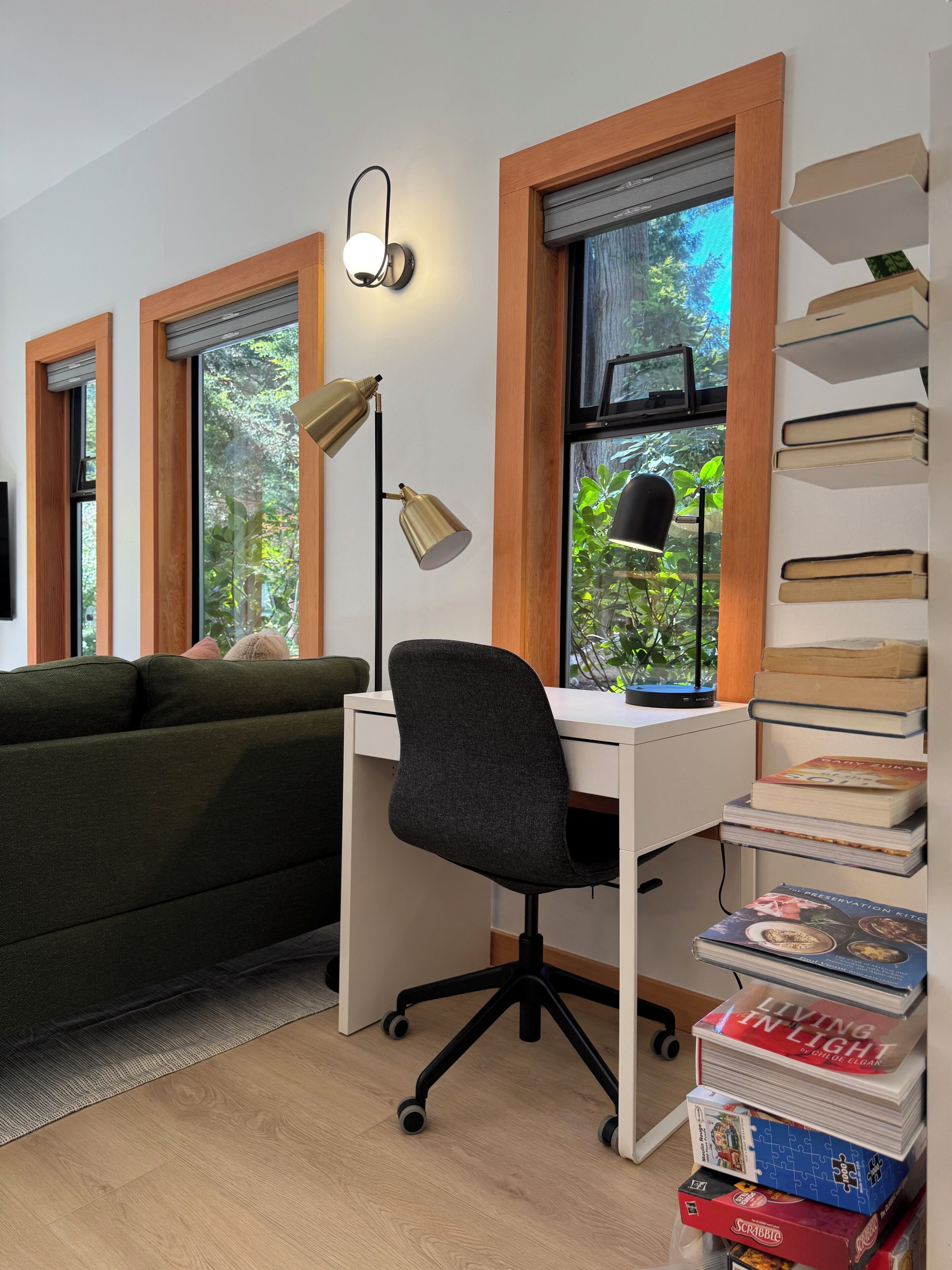 A room with a desk, a chair, a bookshelf, and a window with a view of greenery.