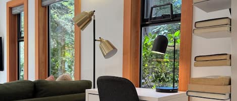 A room with a desk, a chair, a bookshelf, and a window with a view of greenery.