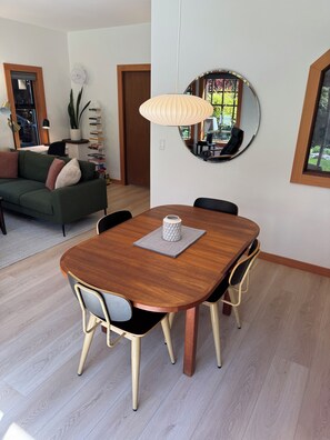 Een eetgedeelte met een houten tafel, vier stoelen en een hanglamp.