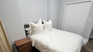 Ein Schlafzimmer mit einem Bett, einem Nachttisch, einer Holzkommode und einer Tür.