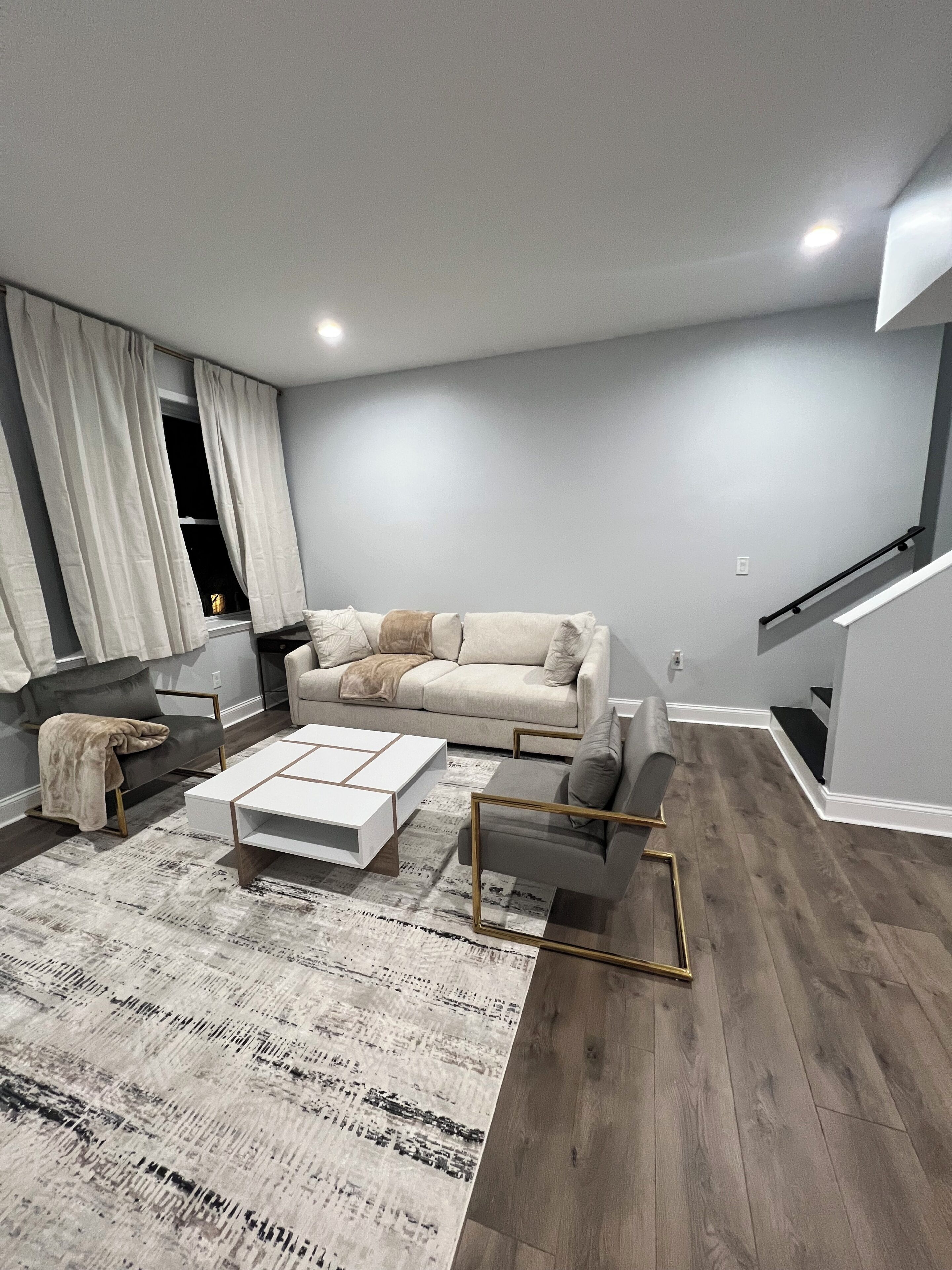 Ein modernes Wohnzimmer mit Sofa, Couchtisch und Treppe.