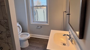 Ein Badezimmer mit Toilette, Waschbecken, Spiegel und Fenster.