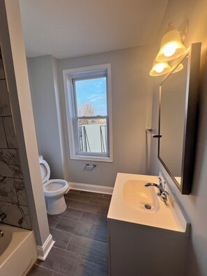 Un bagno con il water, un lavandino, uno specchio e una finestra.