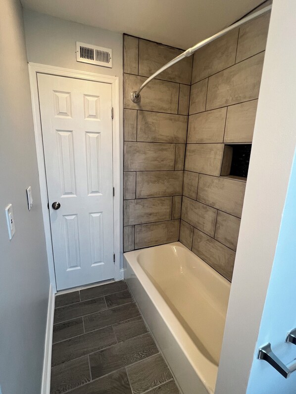 Un bagno con una vasca, uno spazio doccia e una porta.
