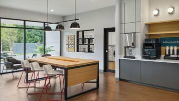 Een moderne keuken met een centraal eiland, barstoelen, hanglampen en een koffiehoek.