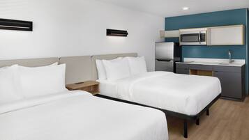 Una habitación de hotel con dos camas, una kitchenette y una mesita de noche.
