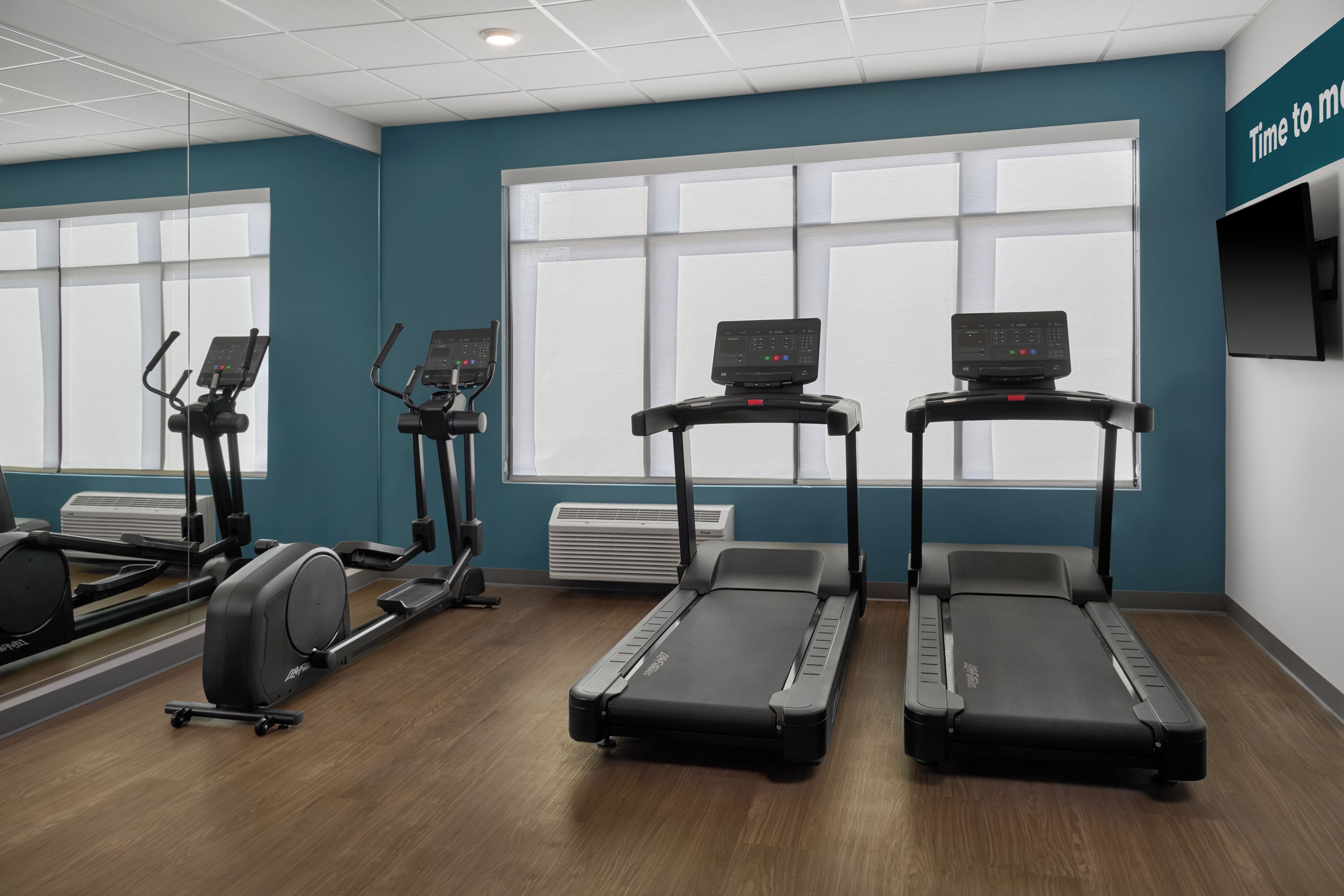 Une salle de sport équipée de tapis de course, de vélos elliptiques et d’un vélo d’appartement.