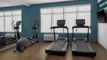 Une salle de sport équipée de tapis de course, de vélos elliptiques et d’un vélo d’appartement.