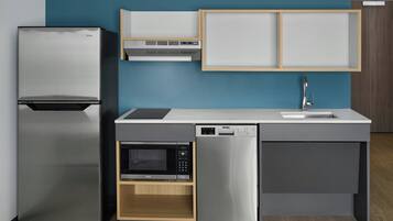 Cocina compacta con refrigerador, microondas y lavavajillas integrados, con un diseño moderno y detalles de madera.