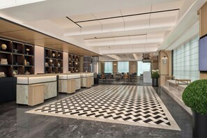 A modern hotel lobby with a check-in counter, seating area, and a patterned floor. - Four Points By Sheraton Changsha South Station (Changsha)