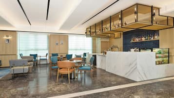 Un moderno vestíbulo de hotel con zona de bar, asientos y mostrador de recepción.