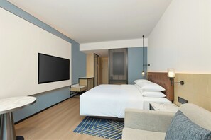 A hotel room with a bed, a TV mounted on the wall, a small table, and a seating area with a couch. - Four Points By Sheraton Changsha South Station (Changsha)