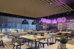 Interior moderno de café com mesas, cadeiras e um letreiro de neon com a frase 'GRAB & GO'.