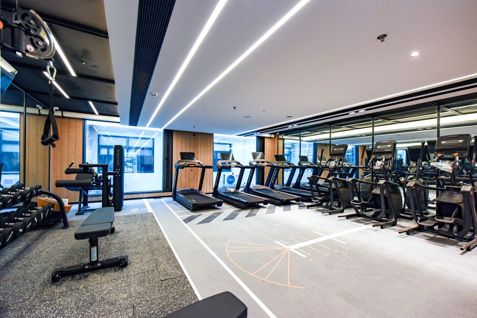 Un gimnasio moderno con cintas de correr, pesas y un espejo grande.