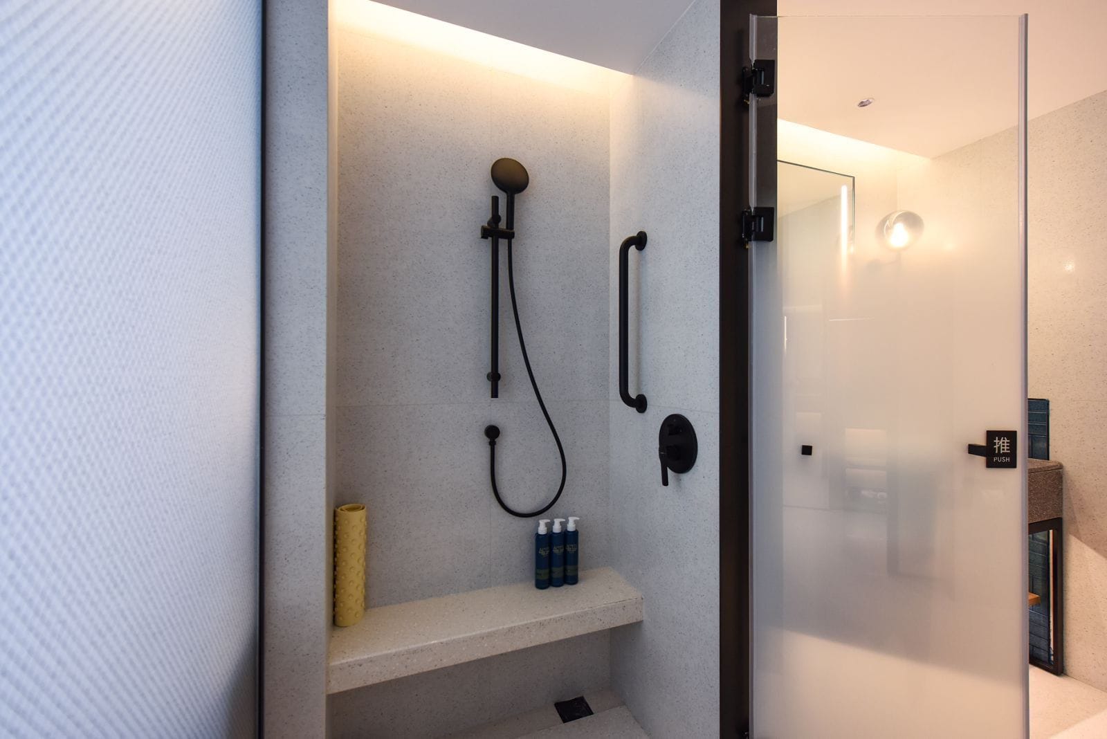 Un bagno moderno con cabina doccia in vetro, porta asciugamani e ripiano con articoli da toilette.
