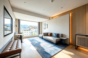 A modern living room with a sofa, a bench, a table, and a large window offering a city view. - Four Points By Sheraton Zhangjiajie National Forest Park (Zhangjiajie)