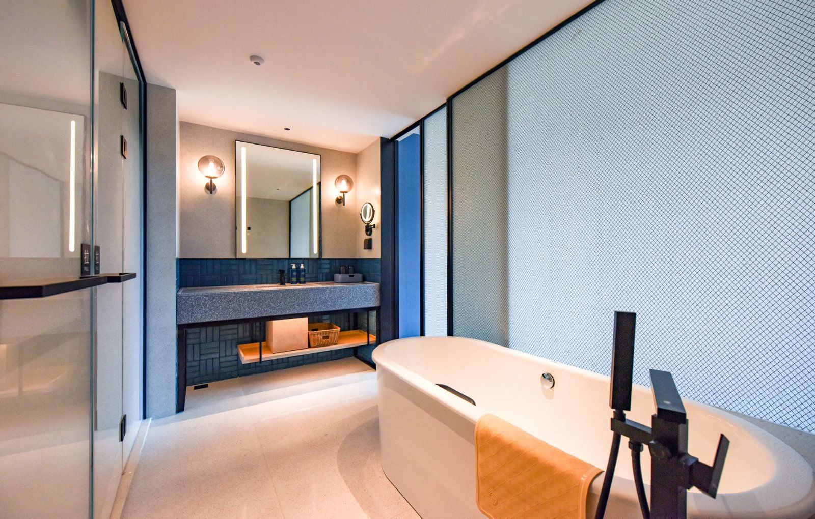 A modern bathroom with a large bathtub, a glass shower enclosure, and a vanity with a mirror and lights.