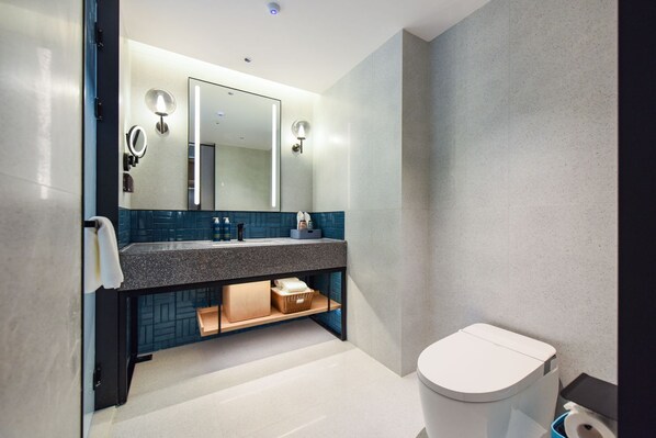 A modern bathroom with a granite countertop, a large mirror, and a white toilet.