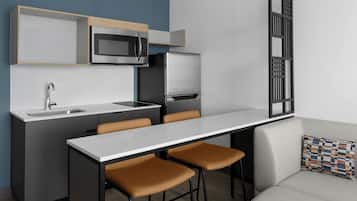 A modern kitchen with a built-in microwave, refrigerator, and sink. There is a dining area with a table and chairs.