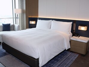 A modern hotel room with a large bed, bedside tables, and a view of the city.