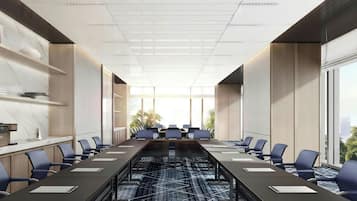 Una sala conferenze moderna con un lungo tavolo, sedie e vista sull'esterno.