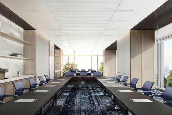 Une salle de conférence moderne, dotée d’une longue table, de chaises et offrant une vue sur l’extérieur.