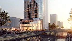 Un hotel moderno de rascacielos con fachada de vidrio reflectante y un área de lounge ejecutiva destacada en la planta baja.