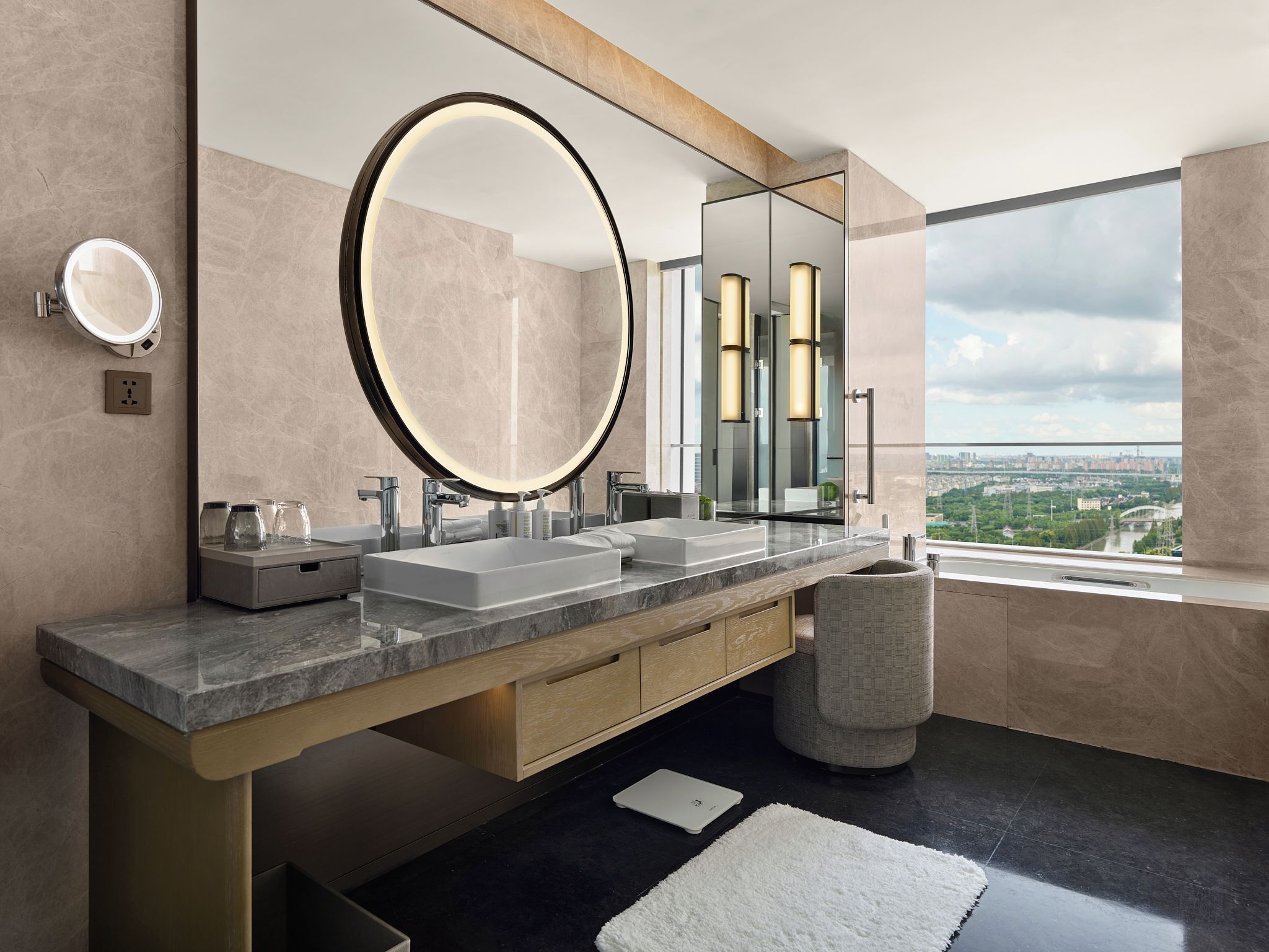 Un bagno moderno con doppio lavabo, uno specchio grande e vista sulla città.