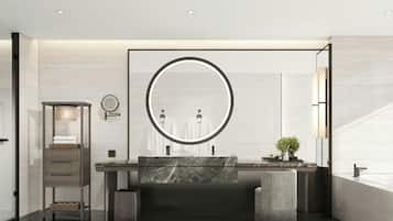 A modern bathroom with a large round mirror, a marble sink, and a small plant.