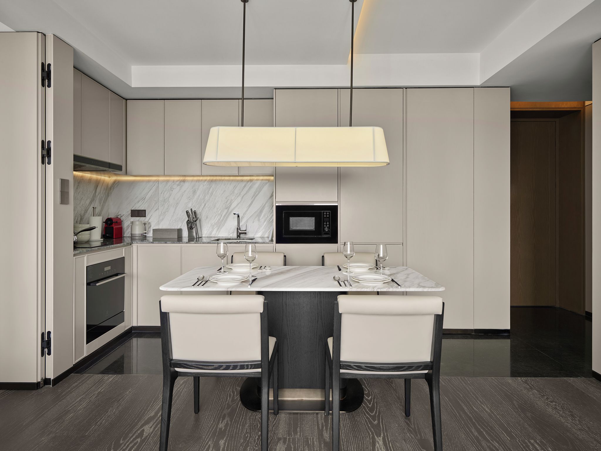 Cocina moderna con encimera de mármol, electrodomésticos integrados y comedor con mesa para cuatro.