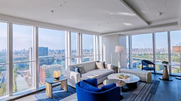 A modern living room with a city view, a sofa, a coffee table, and a blue armchair.
