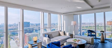 Una sala moderna con vista a la ciudad, un sofá, una mesa de centro y un sillón azul.