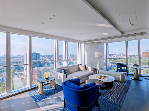 A modern living room with a city view, a sofa, a coffee table, and a blue armchair.