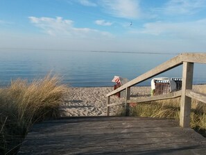 A wooden boardwalk leading to a sandy beach with a clear view of the water. - Holiday Apartment With 1 Bedroom (Heiligenhafen)