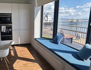 A modern kitchen with built-in appliances and a large window overlooking a pier. - The Hideaway | Stunning Sea Views & Stylish Stay (Vale of Glamorgan)