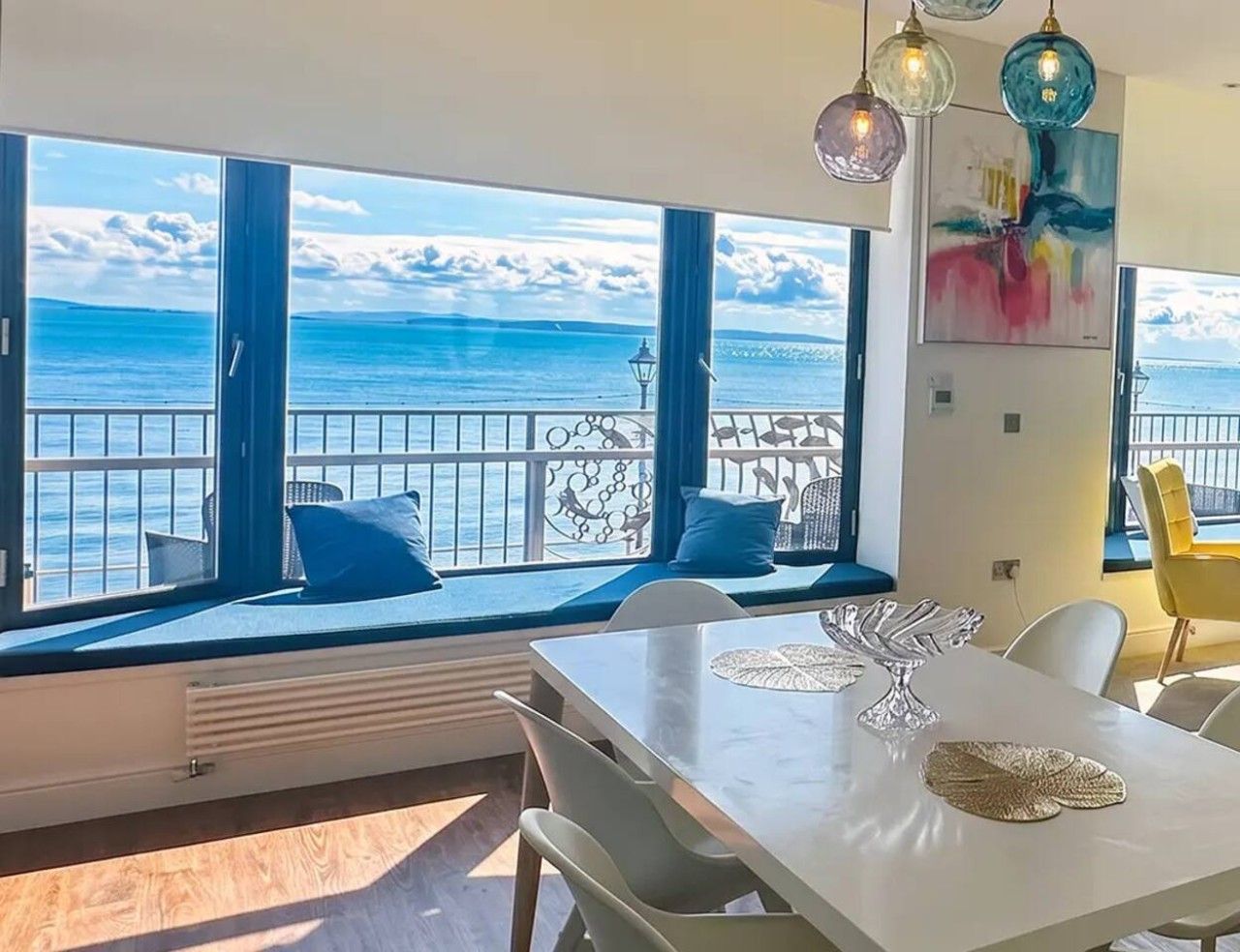 A dining area with a view of the sea, a balcony with seating, and a table with decorative centerpieces.