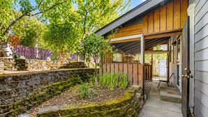 A stone retaining wall with a wooden deck and a covered porch area.