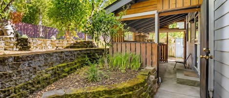 A stone retaining wall with a wooden deck and a covered porch area.