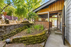 A stone retaining wall with a wooden deck and a covered porch area.