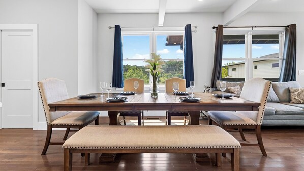 A dining room with a wooden table set for four, flanked by two chairs and a bench.
