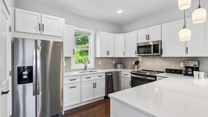 A modern kitchen with white cabinetry, stainless steel appliances, and a large island.