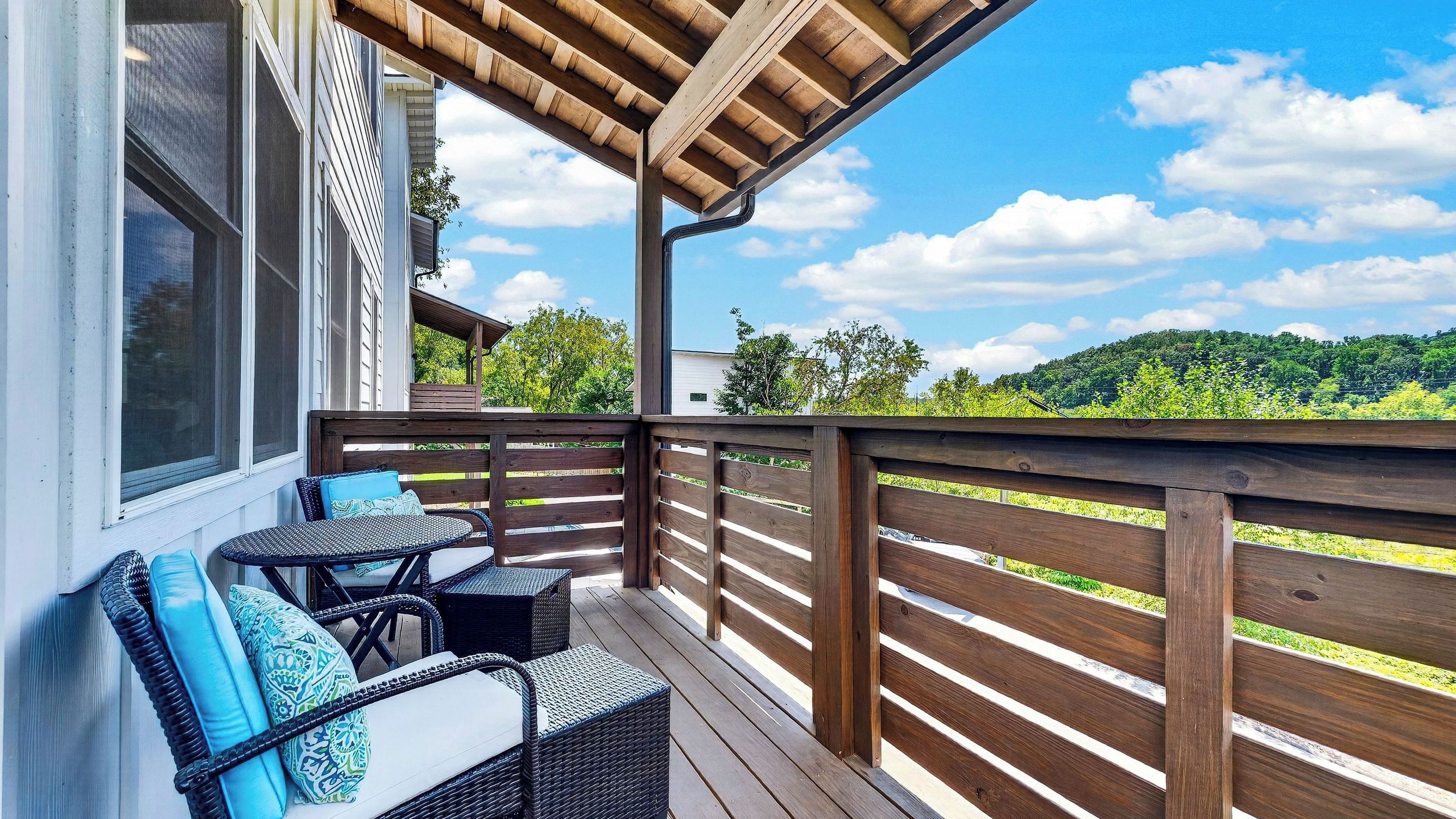 Una terraza de madera con mobiliario exterior y vistas a un paisaje verde.
