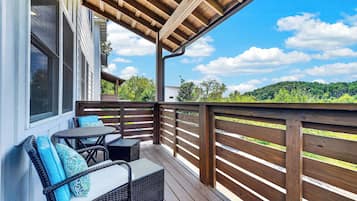 A wooden deck with outdoor furniture and a view of a green landscape.