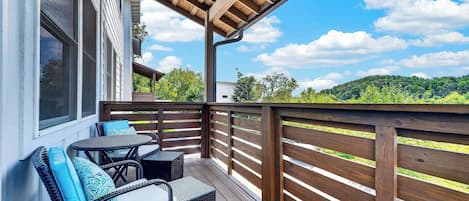 A wooden deck with outdoor furniture and a view of a green landscape.