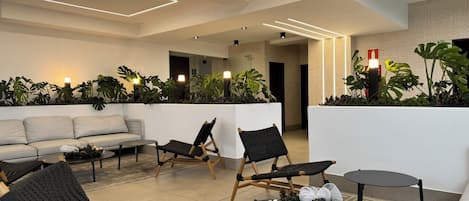 A modern lounge area with a sofa, chairs, a coffee table, and a decorative plant arrangement.