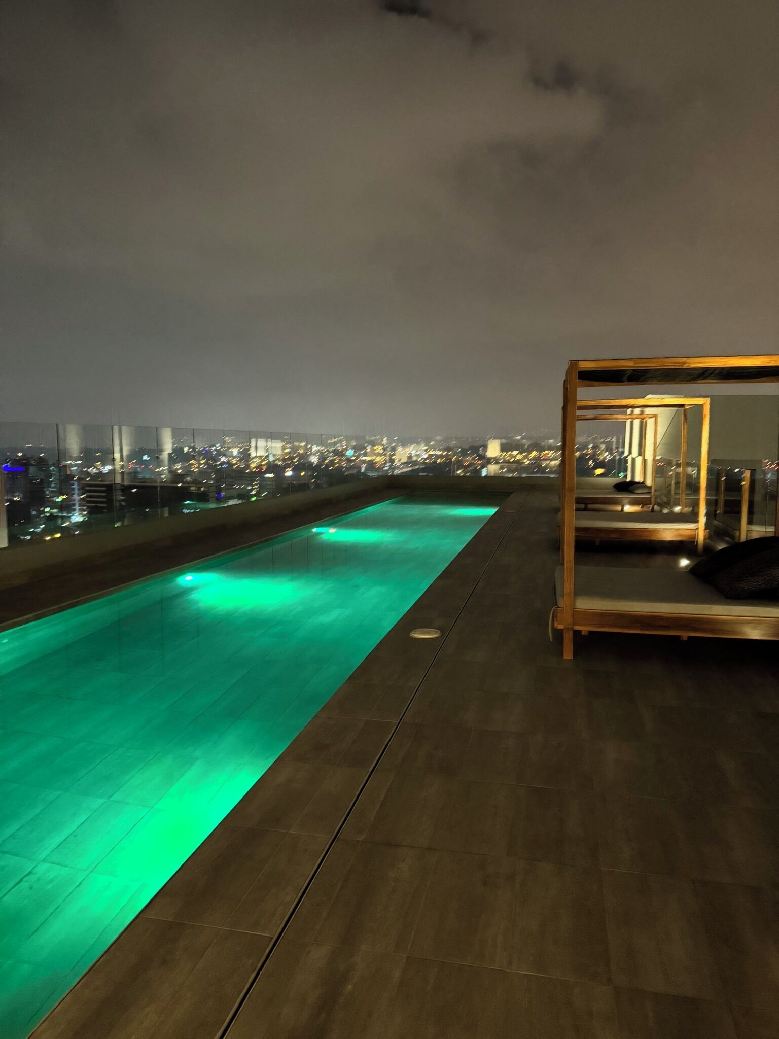 A rooftop pool with a city view at night.