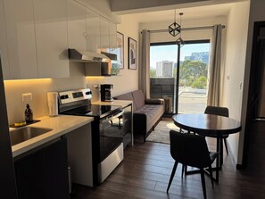 A modern kitchen with a built-in oven, a coffee machine, and a dining area with a round table and chairs. - Luxury One-Bedroom, City Views, Pool & A/C (Ciudad de Guatemala)