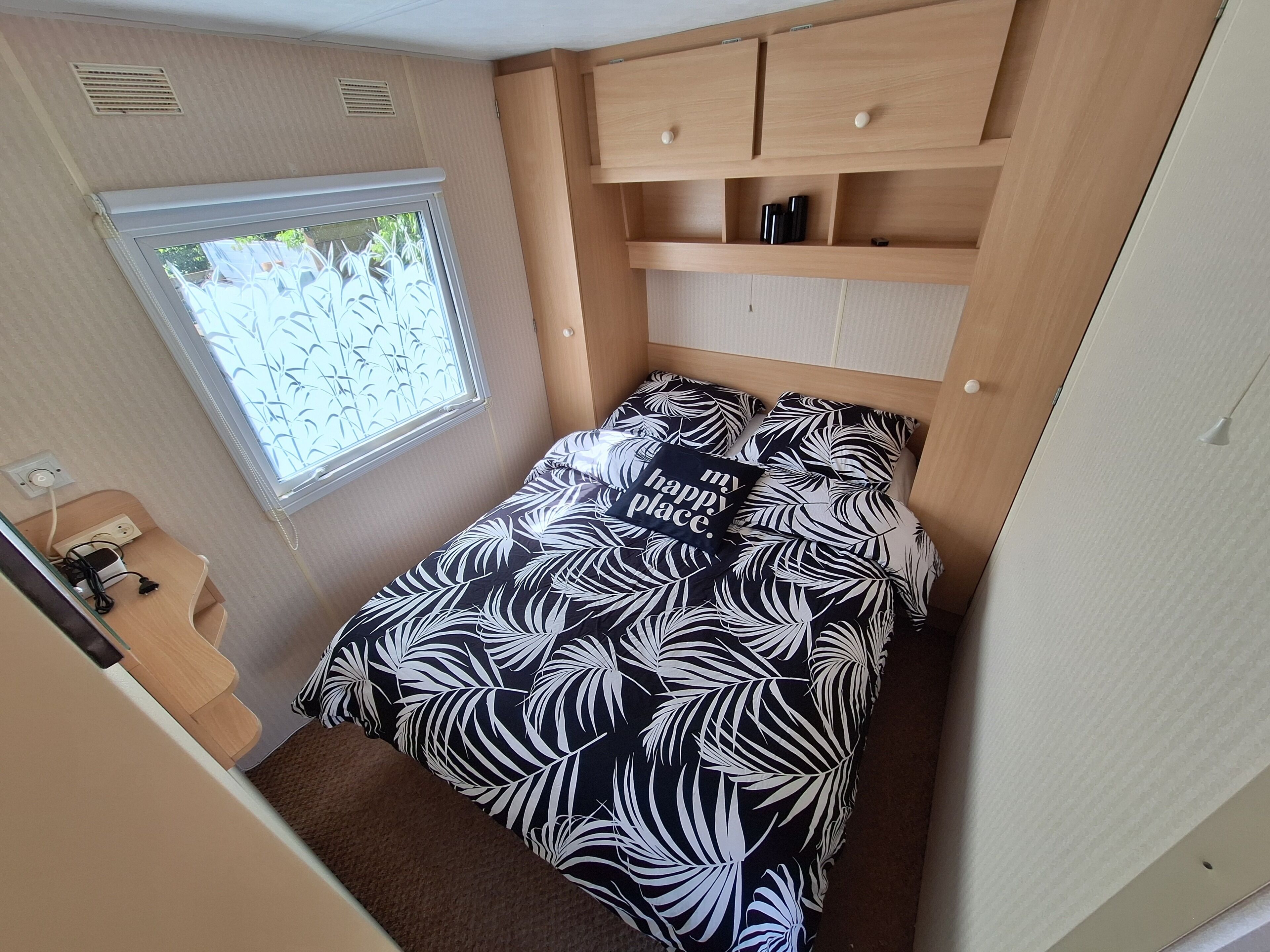 Een compacte slaapkamer met een bed, een raam en een klein bureau.