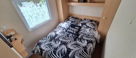 Een compacte slaapkamer met een bed, een raam en een klein bureau.