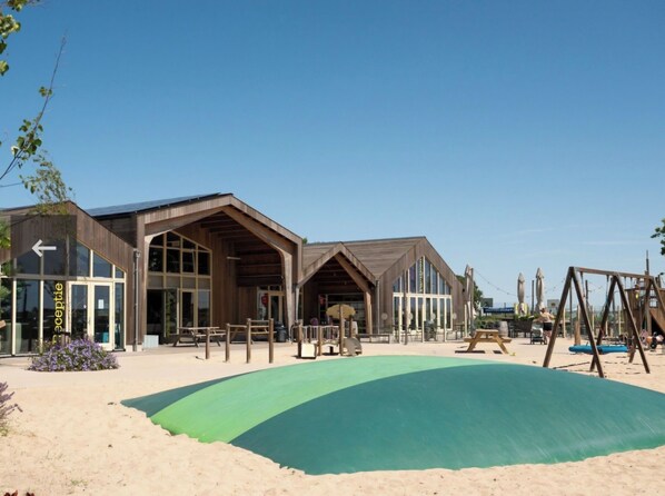 A beachside building with a reception area, large windows, and outdoor seating.